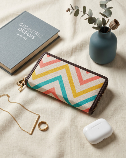 Colorful geometric-patterned pouch with a book, necklace, ring, and small plant on a beige surface.