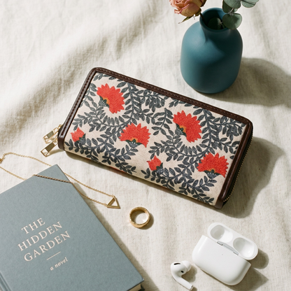 Floral-patterned wallet with a book, ring, and airpods on a light surface