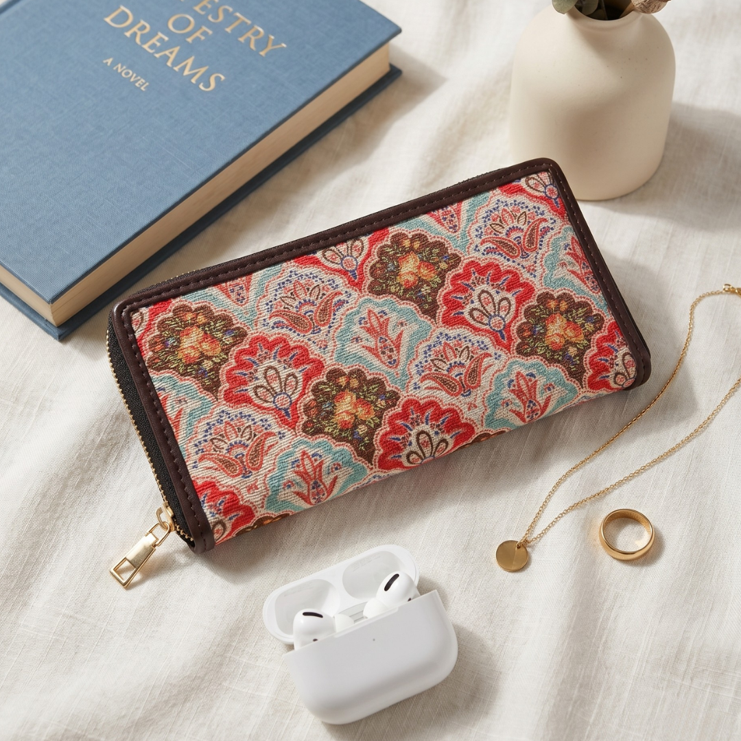 Floral-patterned wallet on a textured surface with a book and airpods case.