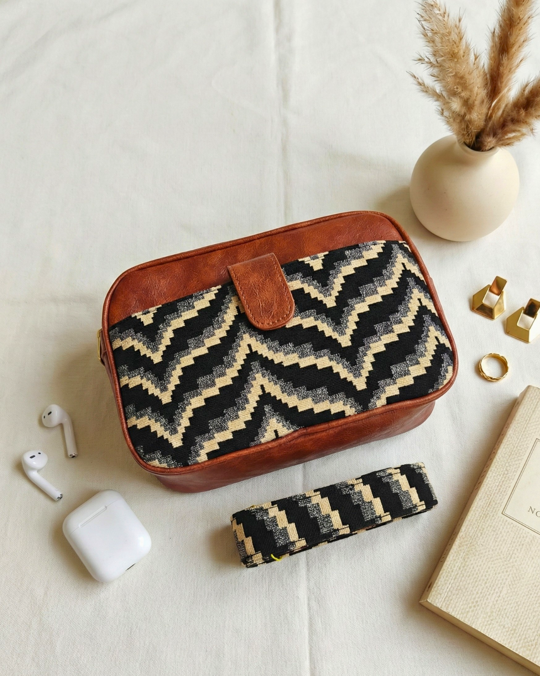 Woven pouch with zigzag pattern on a light surface with accessories around